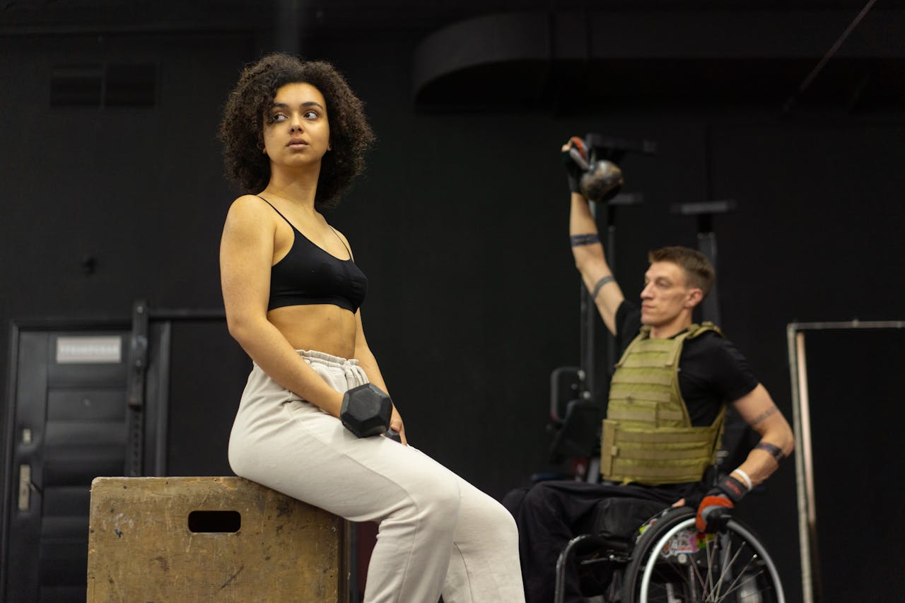 Diverse athletes in gym gear emphasize inclusive fitness with dumbbells and kettlebells.